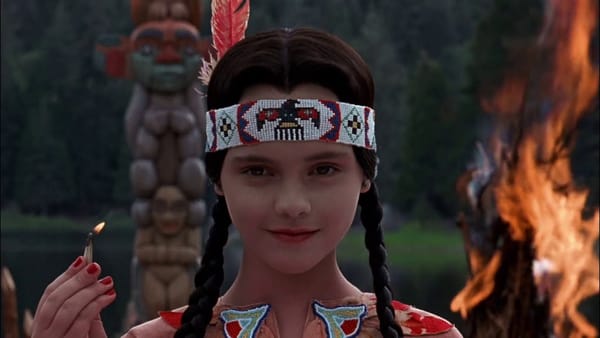 Wenesday Addams dressed as a Native American and holding a mat